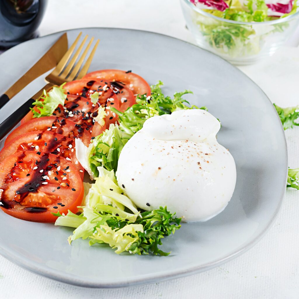 Salad with tomatoes and burrata cheese with lettuce and olive oil